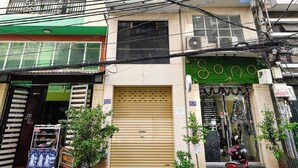 A multi-story building with balconies, a closed shop, and a parked motorcycle. - Huyen Homestay (Ho Chi Minh City)