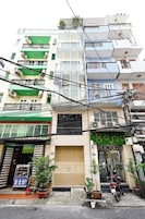 Un edificio de varios pisos con balcones, una tienda cerrada y una motocicleta estacionada.