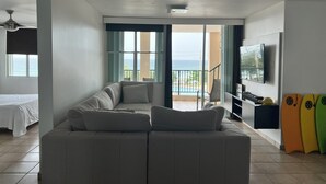 Una sala de estar con sofá, televisión y balcón con vista al mar.