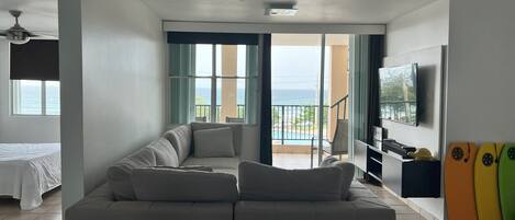 Una sala de estar con sofá, televisión y balcón con vista al mar.