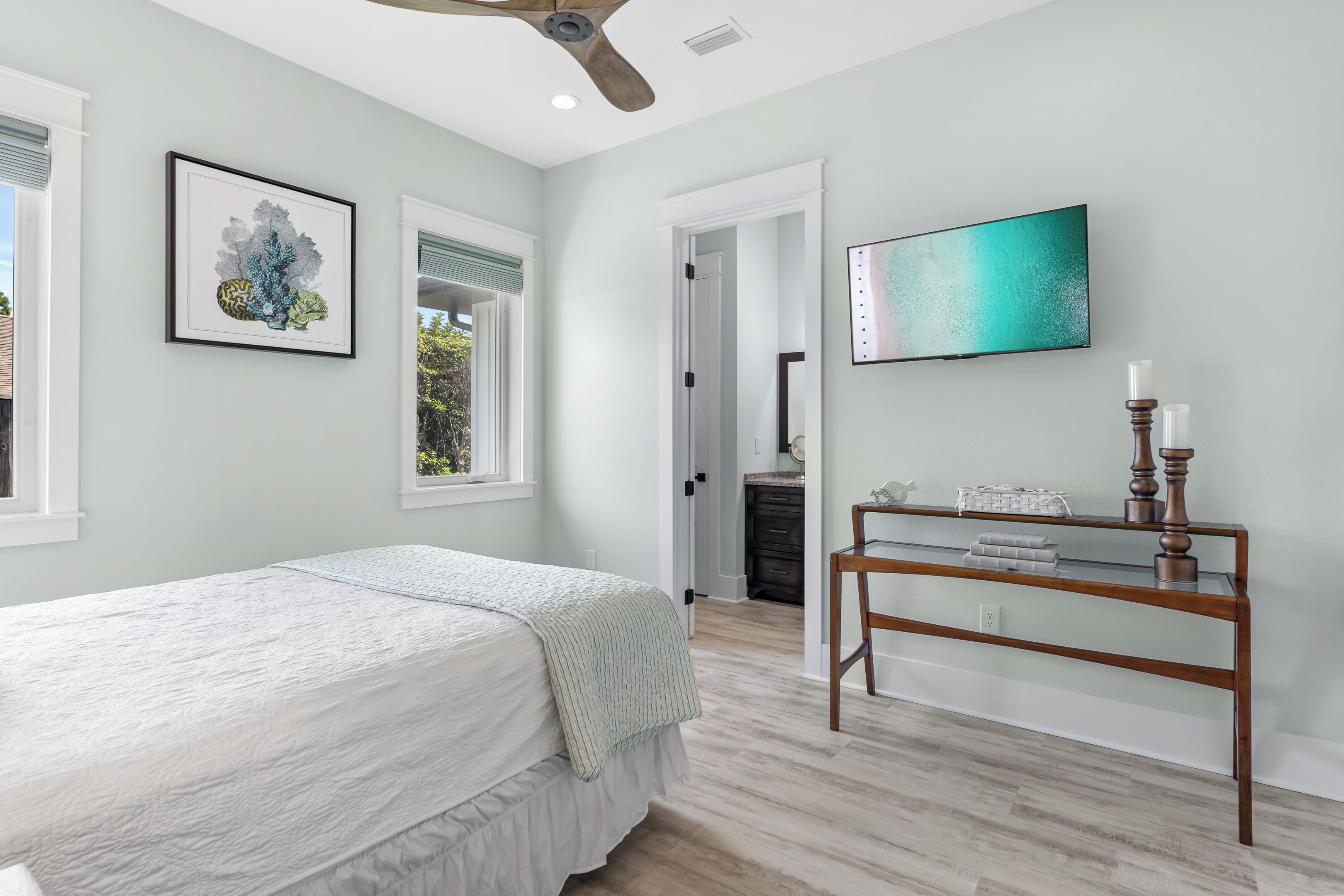 A bedroom with a bed, a desk, a TV, and artwork on the wall.