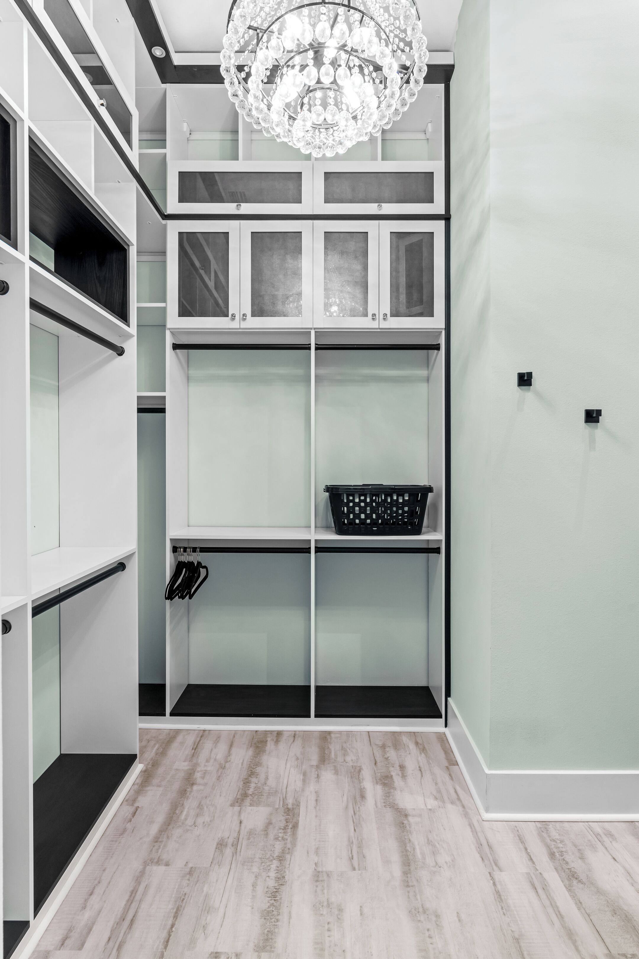 A walk-in closet with multiple shelves, a hanging shoe rack, and a chandelier.