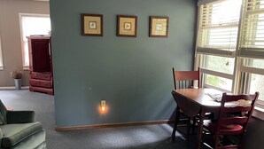 Un comedor con una mesa y sillas, un ventilador de techo y cuadros en la pared.