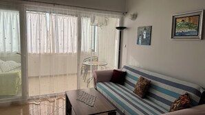 Ein Wohnzimmer mit einer Couch, einem Couchtisch, einem Sessel und Blick durch eine Glastür.