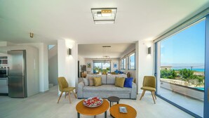 Una sala de estar moderna con un sofá, dos sillones, una mesa de comedor y una zona de cocina.