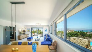 Una sala de estar moderna con un ventanal grande, un comedor y vistas al mar.