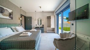 Una habitación de hotel moderna con una cama grande, una zona de estar, un vestidor y un televisor.