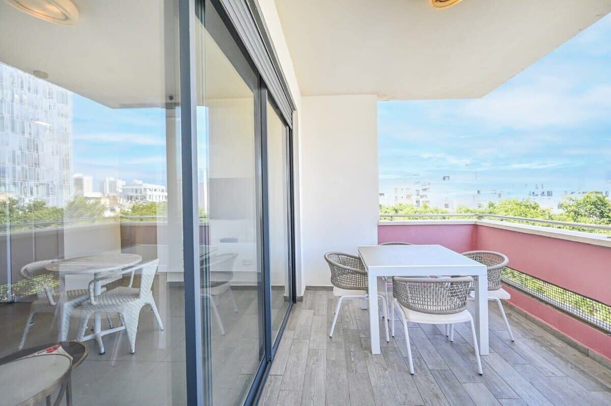 A balcony with a table and chairs, a glass door, and a view of buildings.