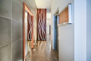 A modern hallway with a polished floor, wooden doors with a unique pattern, and a blue door on the right. - Cozy 2BR with Balcony and Mamad on Dizzengoff by HolyGuest (Tel Aviv-Yafo)