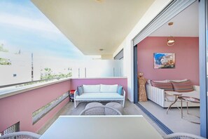 A balcony with a white sofa, a wicker chair, and a small table. - Cozy 2BR with Balcony and Mamad on Dizzengoff by HolyGuest (Tel Aviv-Yafo)