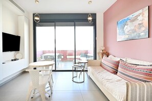 A modern living room with a sofa, two small tables, and a TV. - Cozy 2BR with Balcony and Mamad on Dizzengoff by HolyGuest (Tel Aviv-Yafo)
