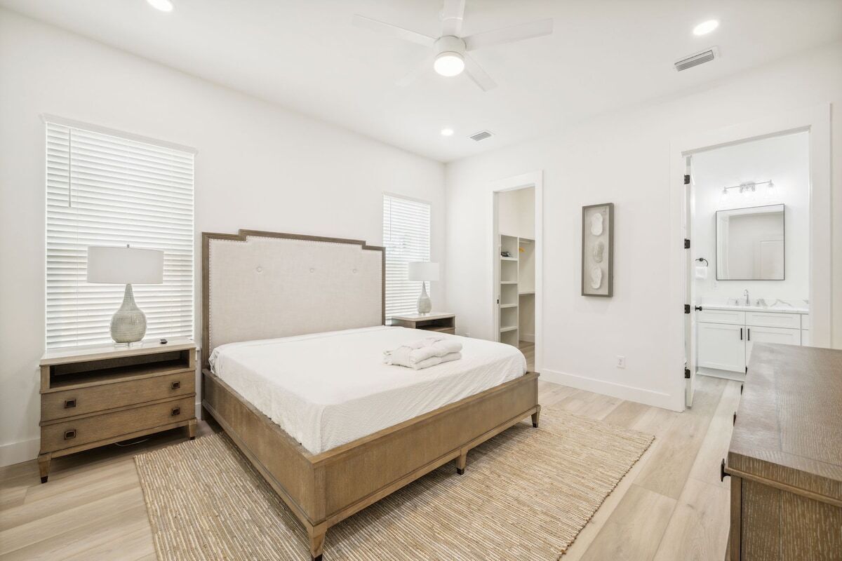 Un dormitorio con cama de madera, mesitas de noche, tocador y vestidor.