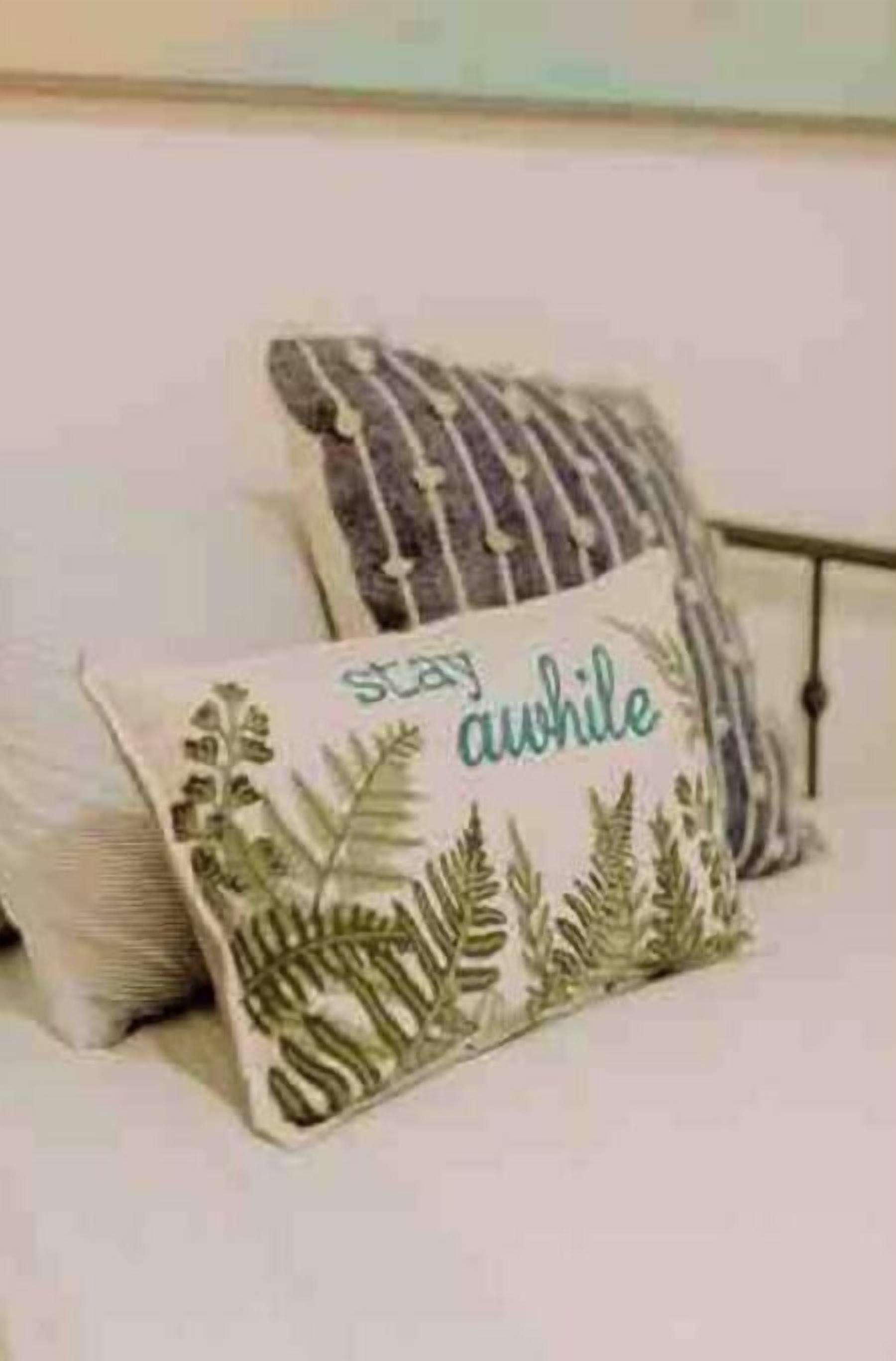 Un lit avec deux coussins décoratifs, l’un orné d’un motif de feuilles et l’autre d’un motif à rayures.