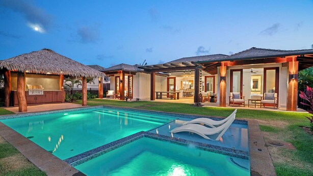 Un resort con piscina, mobiliario exterior y una estructura de techo de paja.