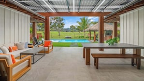 Un espacio exterior moderno con piscina, mobiliario y vistas del paisaje circundante.