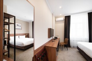 Una habitación de hotel con cama, escritorio, silla, televisor y armario.