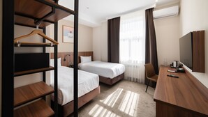 Una habitación de hotel con dos camas, un escritorio, una silla y un televisor.