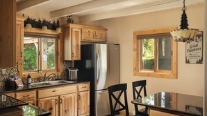 Una cocina con armarios de madera, un refrigerador de acero inoxidable, un lavamanos y una mesa de comedor con sillas.