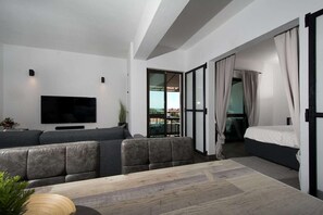 A modern hotel room with a sofa, a flat-screen TV, a bed with curtains, and a balcony view. - Comfy Apt. w/ View – Lagos (Lagos)