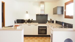 A modern kitchen with white cabinets, a built-in oven, a microwave, and a sink.