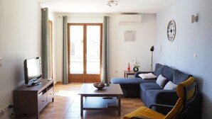 A living room with a television, sofa, coffee table, and a chair.
