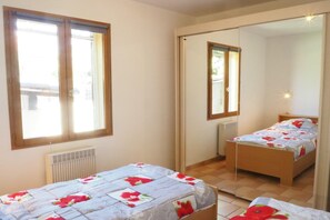 A bedroom with two beds, a radiator, and a window.