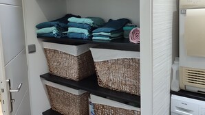 Un lavadero con una lavadora Proline, repisas con ropa doblada y cestos de mimbre.
