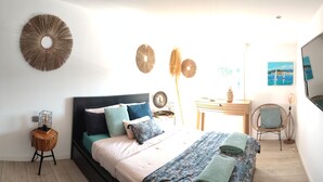 Un dormitorio con cama, mesitas de noche, una silla y adornos en la pared.