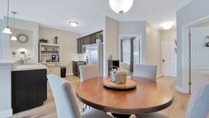 Una cocina moderna con una isla central, un comedor con mesa redonda y una sala de estar con sofá y cortinas.