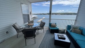 A covered outdoor deck with a glass table, chairs, and a sofa.