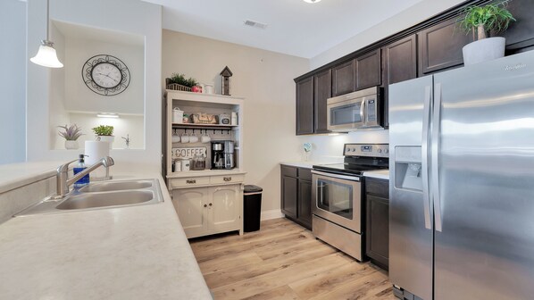 A modern kitchen with stainless steel appliances, a wooden floor, and a built-in microwave above the oven.