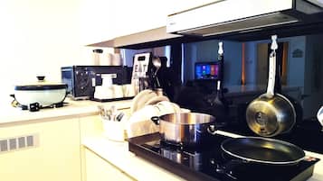A kitchen with a stove, pots, and a microwave.