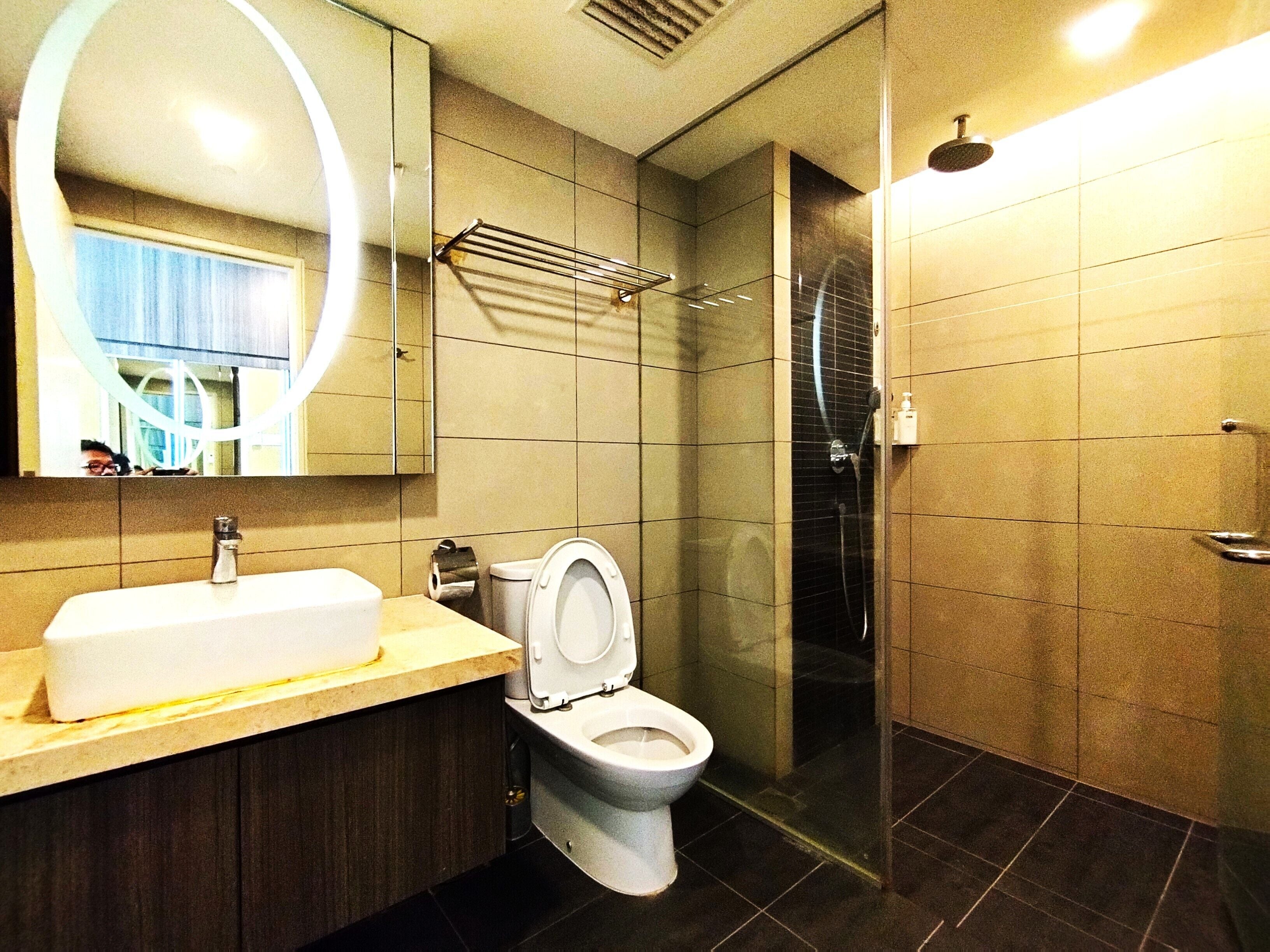 Un baño moderno con inodoro, lavamanos, espejo y ducha.