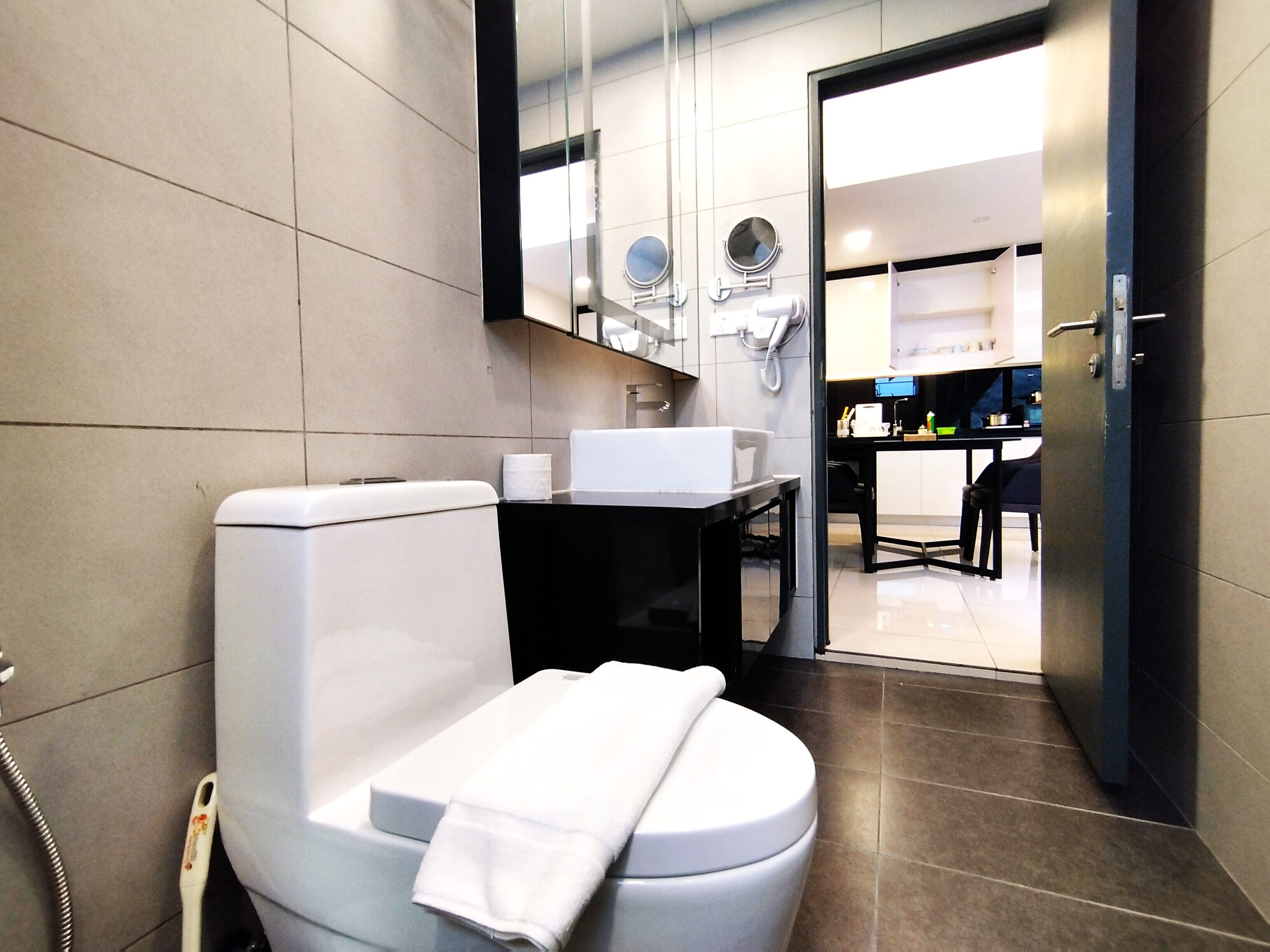 Un baño moderno con inodoro, lavamanos y espejo.