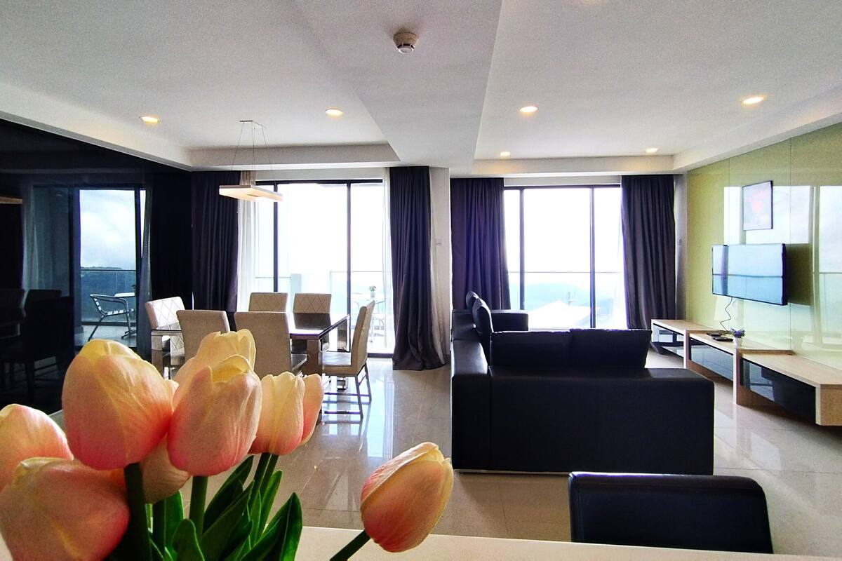 A modern hotel room with a dining area, a sofa, and a TV.