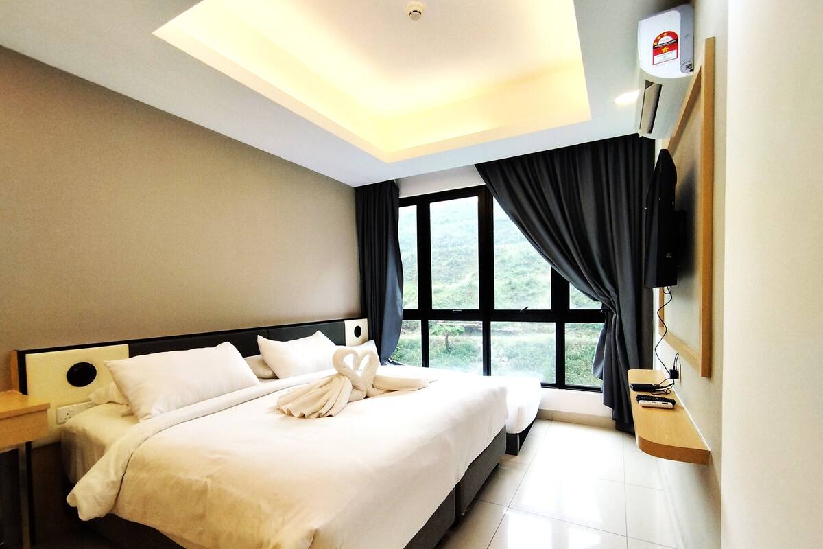 A hotel room with a neatly made bed, a flat-screen TV mounted on the wall, and a large window with curtains.