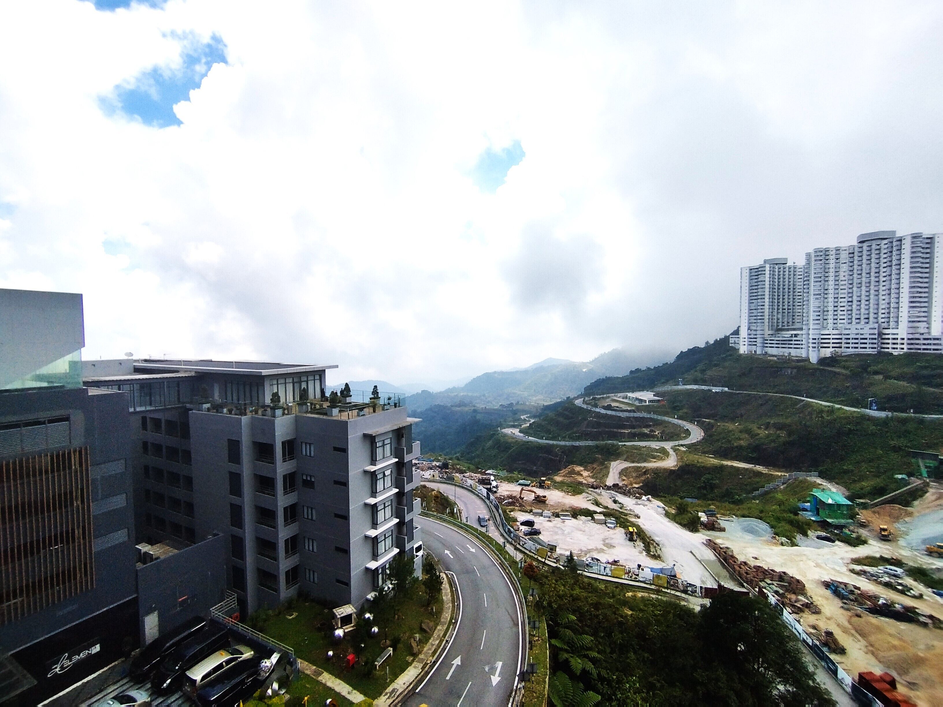 A modern building with a curved road and construction site in the background.