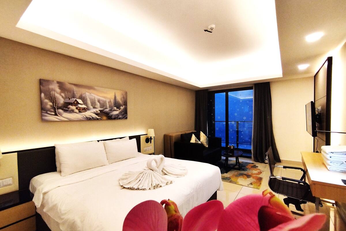 A hotel room with a bed, a desk, a chair, a TV, and a painting on the wall.