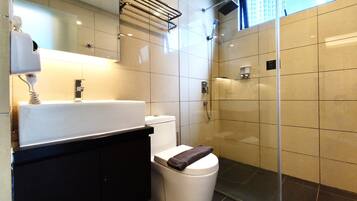 A modern bathroom with a white sink, black countertop, and a glass shower enclosure.