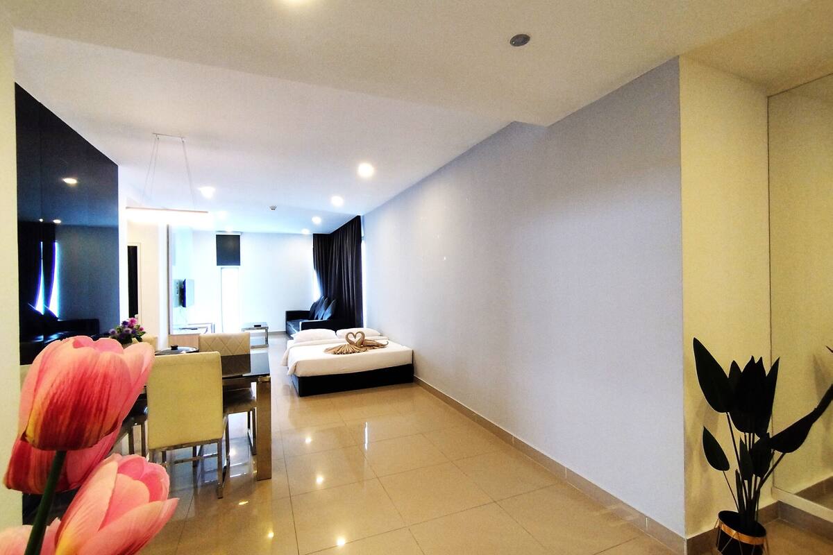 A modern hotel room with a bed, a desk, and a dining area.