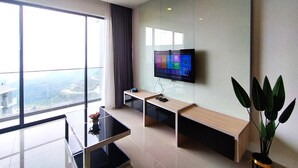 Ein modernes Hotelzimmer mit einem großen Fenster, einem an der Wand befestigten Flachbildfernseher, einer hölzernen Bank und einem kleinen Tisch mit einem Blumenstrauß.