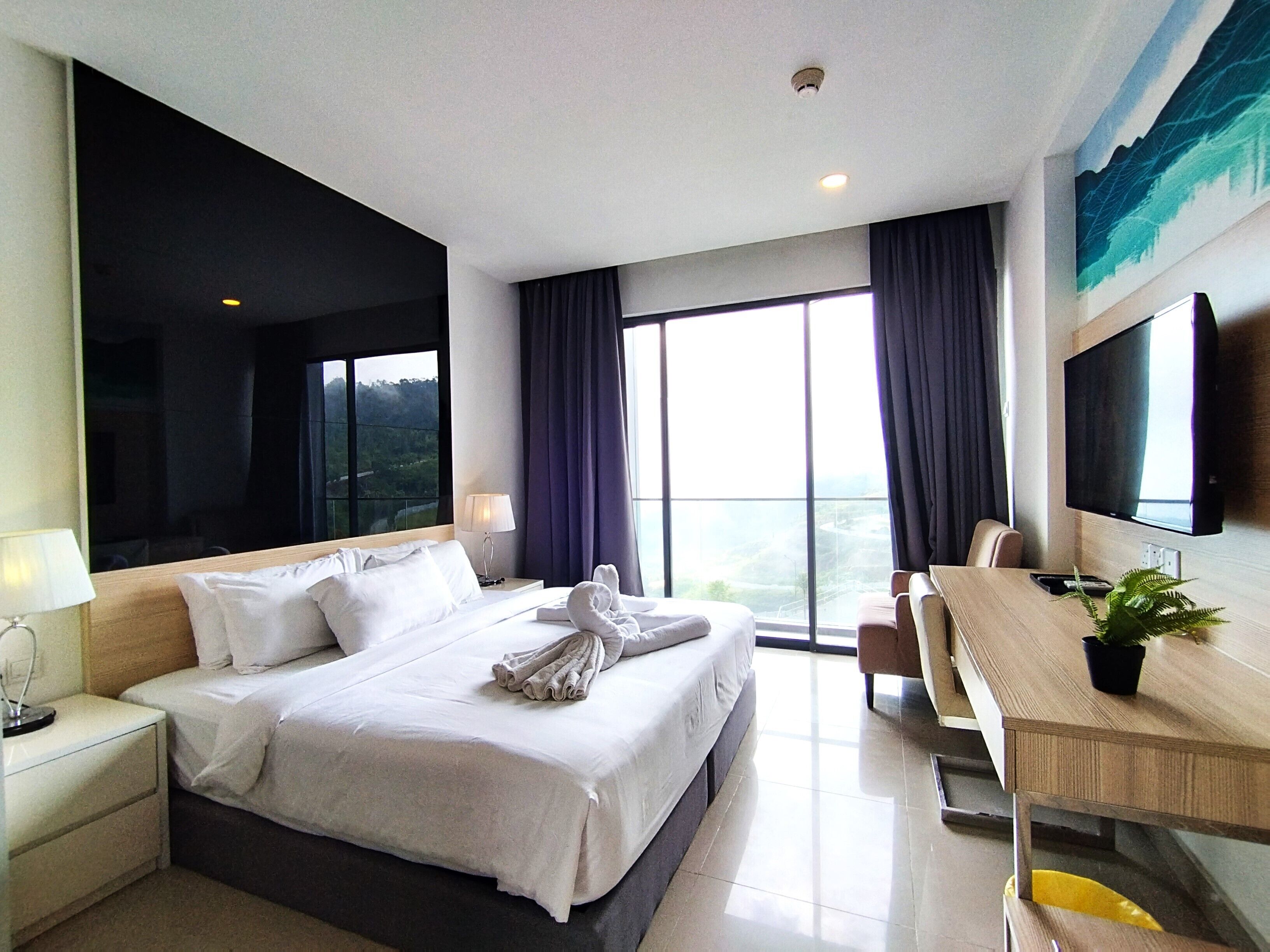 Habitación de hotel con una cama grande, un escritorio, una silla, un televisor y una ventana con vistas.