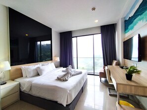 Habitación de hotel con una cama grande, un escritorio, una silla, un televisor y una ventana con vistas.