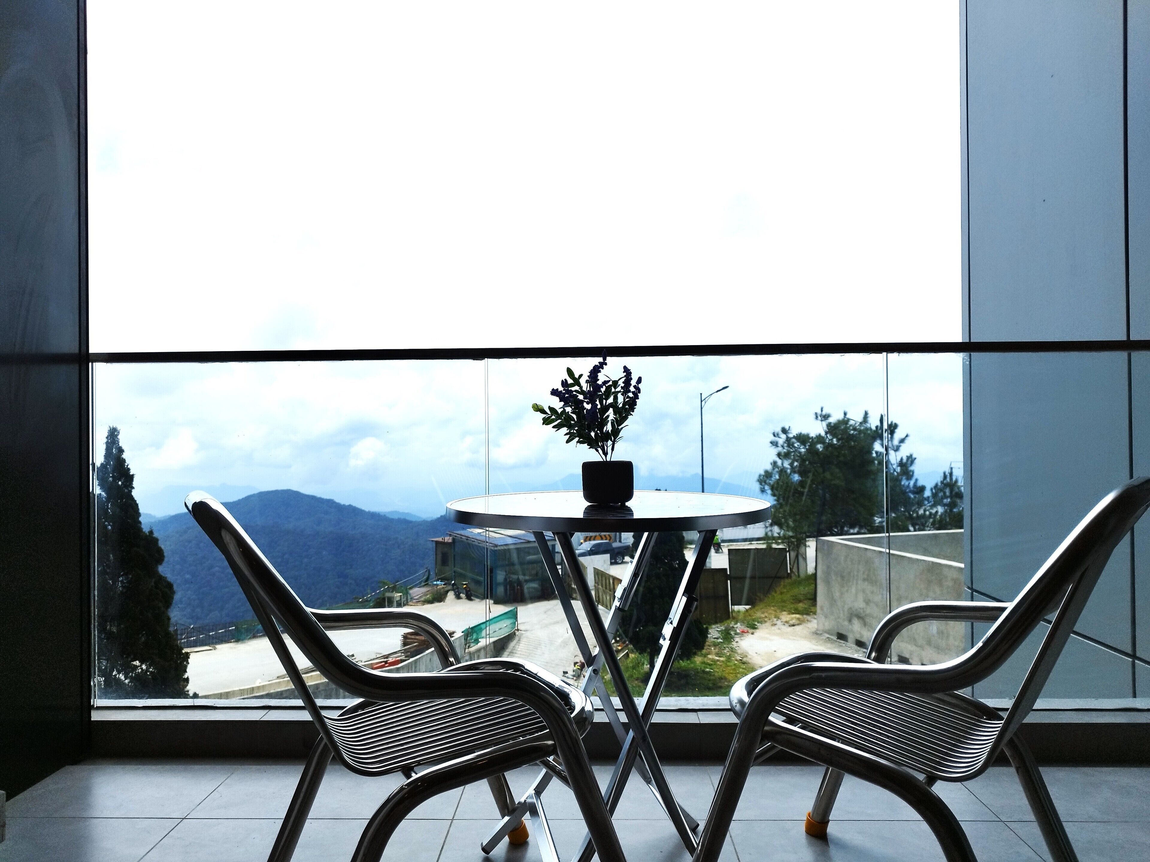 Un balcon avec deux chaises et une table, donnant sur un paysage montagneux.