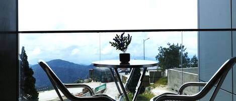 Un balcón con dos sillas y una mesa, con vistas a un paisaje montañoso.