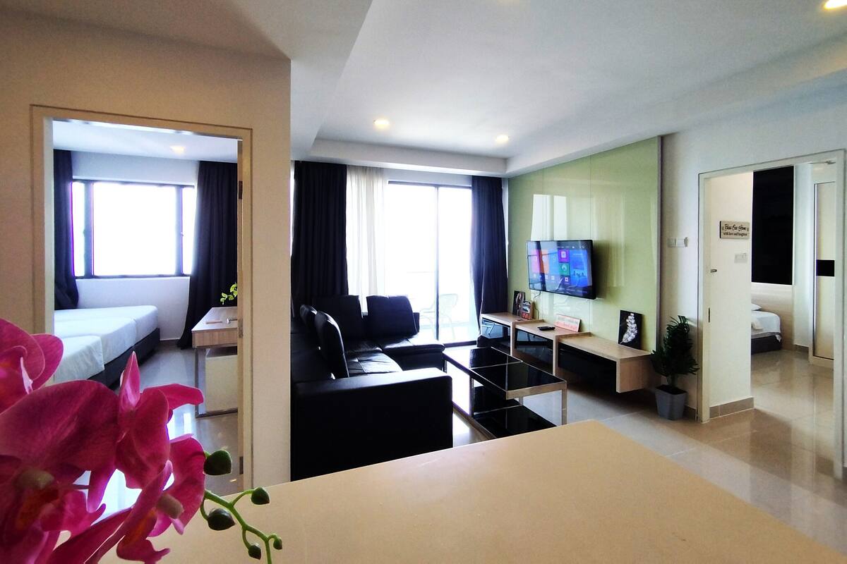 A modern hotel room with a bed, a desk, a chair, a TV, and a plant.