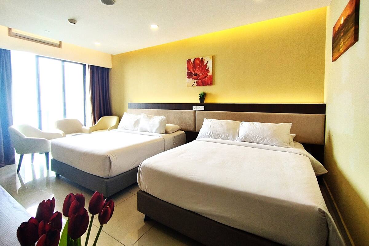 A hotel room with two beds, a chair, and a window with curtains.