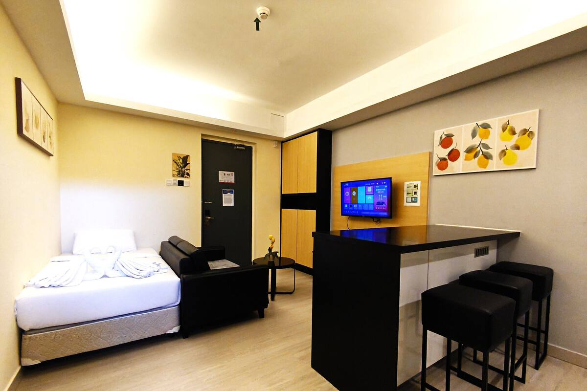 A compact hotel room with a bed, a desk, and a TV.