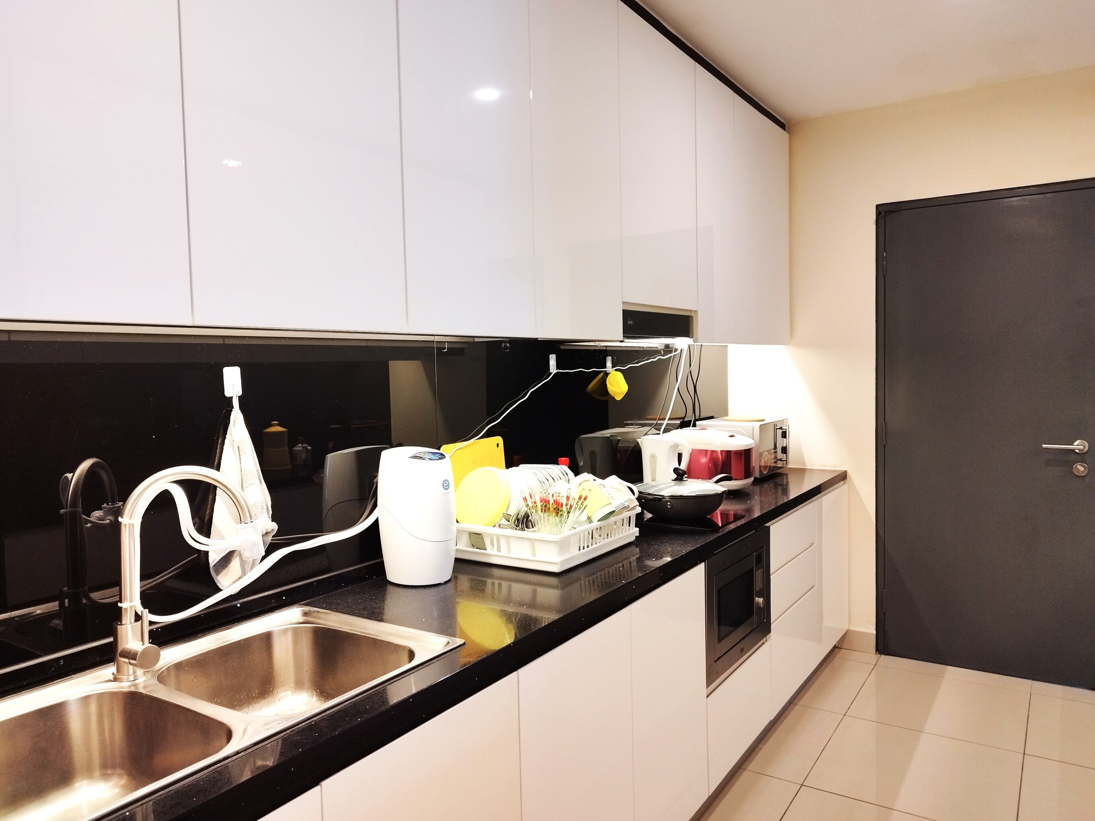 A modern kitchen with stainless steel appliances, a black countertop, and white cabinets.