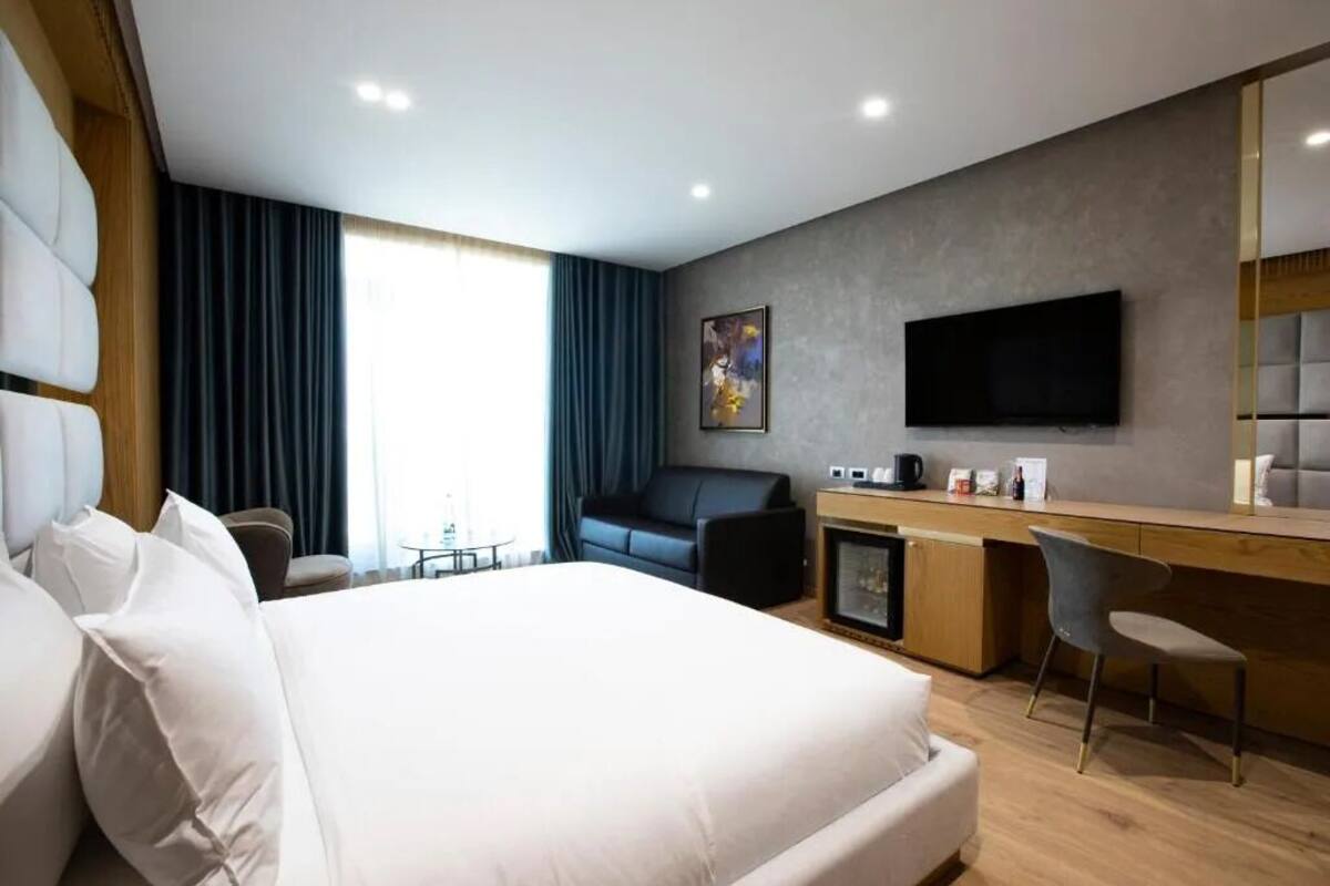 Camera d'albergo con un letto grande, una scrivania, una TV a schermo piatto e un'area ristoro.